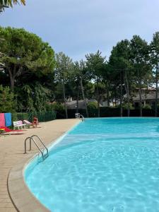 una grande piscina blu con sedie e alberi di Residenza Mayla a Lignano Sabbiadoro