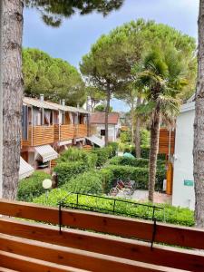 vista su una casa con alberi e panchina di Residenza Mayla a Lignano Sabbiadoro