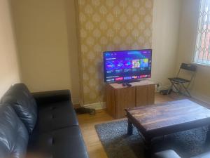 a living room with a couch and a flat screen tv at Transformative housing Laurie avenue in Nottingham