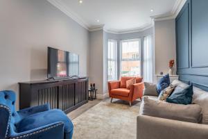 a living room with a tv and a couch and chairs at Luxury Edwardian Townhouse in Belfast in Belfast