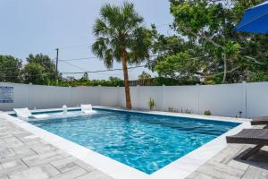 einen Pool mit zwei Stühlen und einer Palme in der Unterkunft Quaint Cottage in a South Sarasota Neighborhood in Sarasota + 42 Fotos