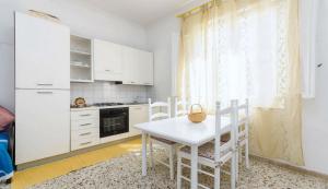 uma cozinha branca com uma mesa e cadeiras brancas em Pepoli Apartment up 4pax Parking em Trapani