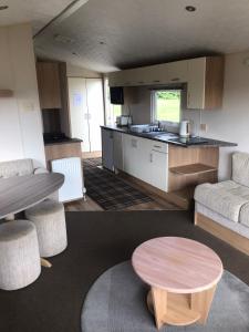 a living room with a table and a kitchen at 48 Oak Village Grange Leisure Park in Mablethorpe