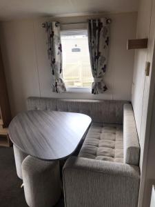a table and a couch in a room with a window at 48 Oak Village Grange Leisure Park in Mablethorpe