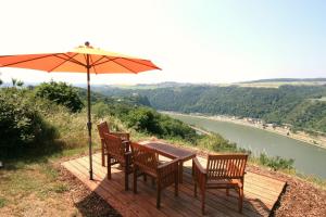 a table and chairs with an umbrella and a river at Loreley Hills in Sankt Goarshausen