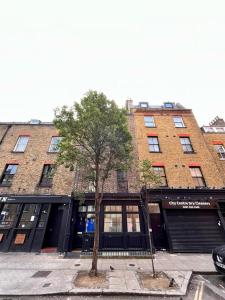 un grande edificio in mattoni con un albero di fronte di 4 floor Apartment in Covent Garden a Londra