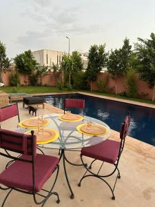 une table en verre avec trois chaises assises sur une terrasse dans l'établissement Villa Novia, à Marrakech