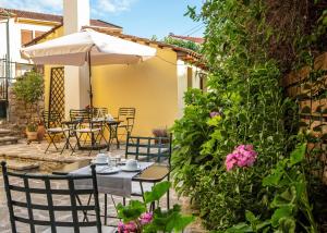 un patio al aire libre con mesas, sillas y flores en Kastro Guesthouse en Ioánina