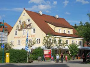 un gran edificio blanco con techo rojo en Hotel zur Post, en Herrsching am Ammersee