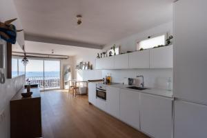 cocina con armarios blancos y vistas al océano en La Panoràmica del Mar, en Tarragona