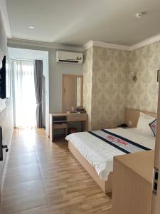迪石的住宿－Ngoc Thanh Hotel，一间卧室配有一张床、一张书桌和一个窗户。
