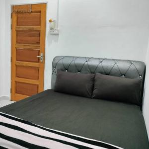 Bett mit schwarzem Kopfteil in einem Zimmer in der Unterkunft KUALA TERENGGANU GUESTHOUSE-FREE WIFI-NEAR NASI DAGANG ATAS ToL-UNIT A-1 BILIK AIRCOND 2 BILIK KIPAS in Kuala Terengganu