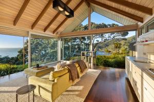 a living room with large windows and the ocean at The Glasshouse in Whangarei Heads