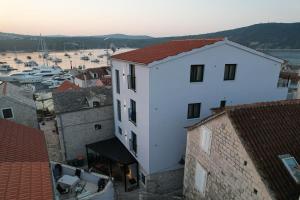 a large white building with a harbor in the background at Azalea Dalmacija Luxury Rooms and Apartments in Primošten