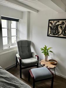 a bedroom with a chair and a ottoman and a table at Sunbjerre B&B in Lille Dalby