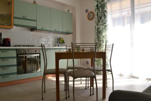 een keuken met groene kasten en een tafel en stoelen bij Casa Ventitré in Balestrate +31 foto's