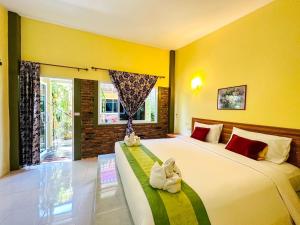two beds in a room with yellow walls at Lanta Baan Nok Resort in Ko Lanta