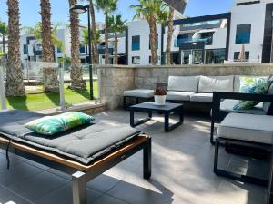 un patio con sofá, sillas y palmeras en Casa La Zenia, en Playas de Orihuela