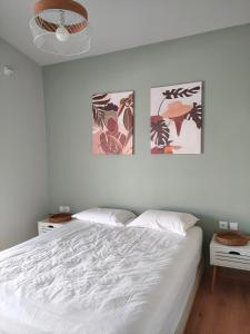 a bedroom with a white bed and two pictures on the wall at Feel like Home Villa in Schinias