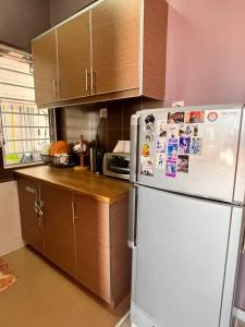 a kitchen with a white refrigerator and wooden cabinets at Glory beach private PD in Port Dickson