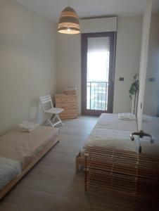 a bedroom with two beds and a chair and a window at Appartamento Centro dei Venti in Montesilvano