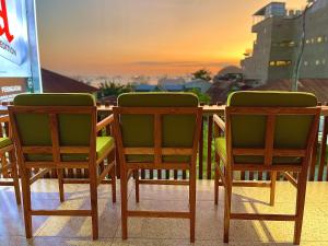 2 Stühle und ein Tisch mit Sonnenuntergang im Hintergrund in der Unterkunft Puu Pau Hotel & Coffee Shop in Labuan Bajo