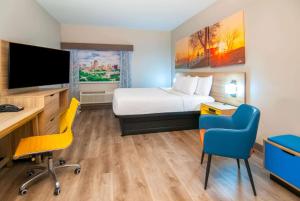 a hotel room with a bed and a desk and chairs at Days Inn & Suites by Wyndham San Antonio North/Stone Oak in San Antonio