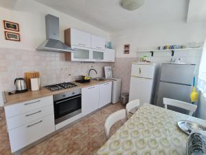 a kitchen with white appliances and a table and a dining room at Apartments Ivan in Zubovići