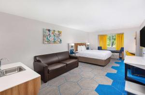 a hotel room with a bed and a couch at Microtel Inn & Suites Columbus North in Columbus