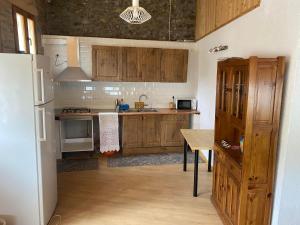 cocina con armarios de madera, mesa y nevera en Casa Casteller, en Arfa