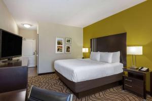 a hotel room with a bed and a flat screen tv at La Quinta by Wyndham Artesia in Artesia