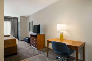 Comfort Suites Denham Springs في دينهام سبرينغز: غرفة بالفندق بها مكتب وسرير وتلفزيون