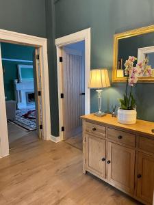 a room with a dresser with a lamp and flowers on it at Luxury Victorian spacious flat in Glasgow