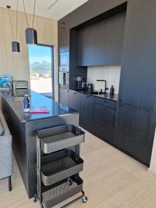 uma cozinha com um balcão preto e um lavatório em Classy Cabin Lofoten em Kleppstad
