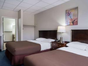 a hotel room with two beds and a lamp at Travelodge by Wyndham Wetaskiwin in Wetaskiwin