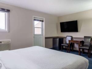 Habitación de hotel con cama, escritorio y TV. en Travelodge by Wyndham Wetaskiwin, en Wetaskiwin