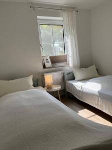 a bedroom with two beds and a window and a table at Ferienwohnung II im idyllischen Gulfhof in Krummhörn