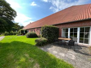 a house with a table and chairs in the yard at Ferienwohnung II im idyllischen Gulfhof in Krummhörn +12 photos
