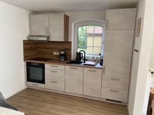 a small kitchen with white cabinets and a window at Ferienwohnung II im idyllischen Gulfhof in Krummhörn