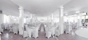 un comedor con mesas blancas y sillas blancas en Hotel Sant'Agata en SantʼAgata sui Due Golfi