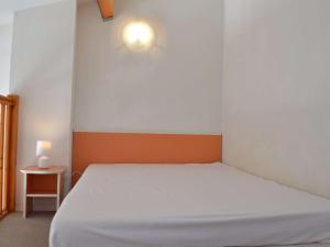 Un dormitorio con una cama blanca y una luz en la pared en Maison Narbonne, 2 pièces, 4 personnes - FR-1-229B-39, en Narbona