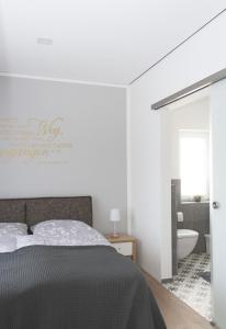 a white bedroom with a bed and a bathroom at FreiRaum in Vöhringen