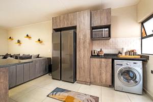 a kitchen with a refrigerator and a washing machine at Airport Heights in Boksburg