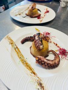 zwei weiße Teller mit Essen auf dem Tisch in der Unterkunft Admiral Hotel Villa Erme in Desenzano del Garda