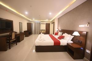 Dormitorio con cama, escritorio y TV en Hotel Bhagavath Gardens, en Chengannūr