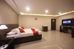 1 dormitorio con 1 cama y TV en Hotel Bhagavath Gardens, en Chengannūr