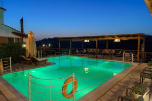 a pool at night with tables and chairs at Bacchus Villa in Archea Pissa