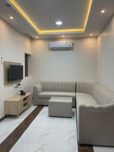 uma sala de estar com um sofá e uma televisão em أبراج الجزيرة em Al-Hofuf