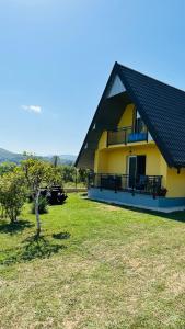 een geel huis met een zwart dak en een tuin bij B&B Hills Bihać in Bihać