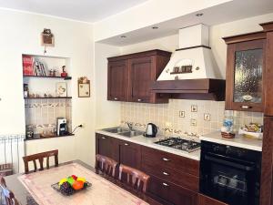 kuchnia z drewnianymi szafkami, stołem i kuchenką w obiekcie Calacta casa mia w mieście Caronia